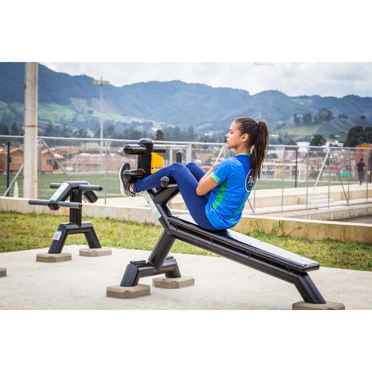 Mujer entrenando en la banca abdominal inclinada de TMGYM, vista lateral