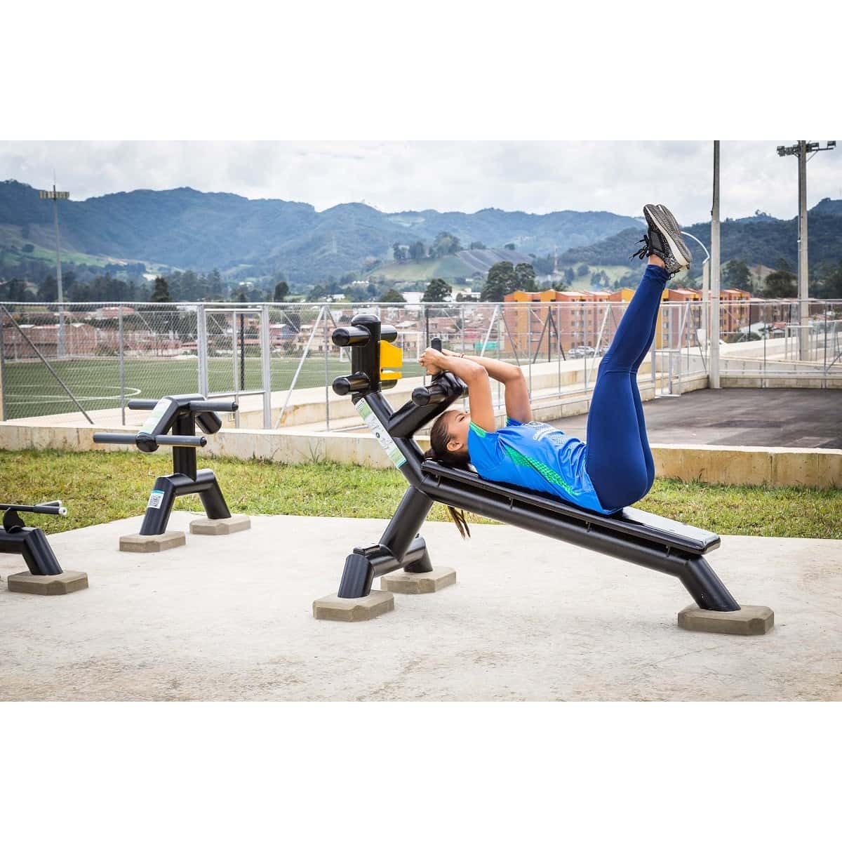 Mujer con las piernas arriba en la banca abdominal inclinada de TMGYM