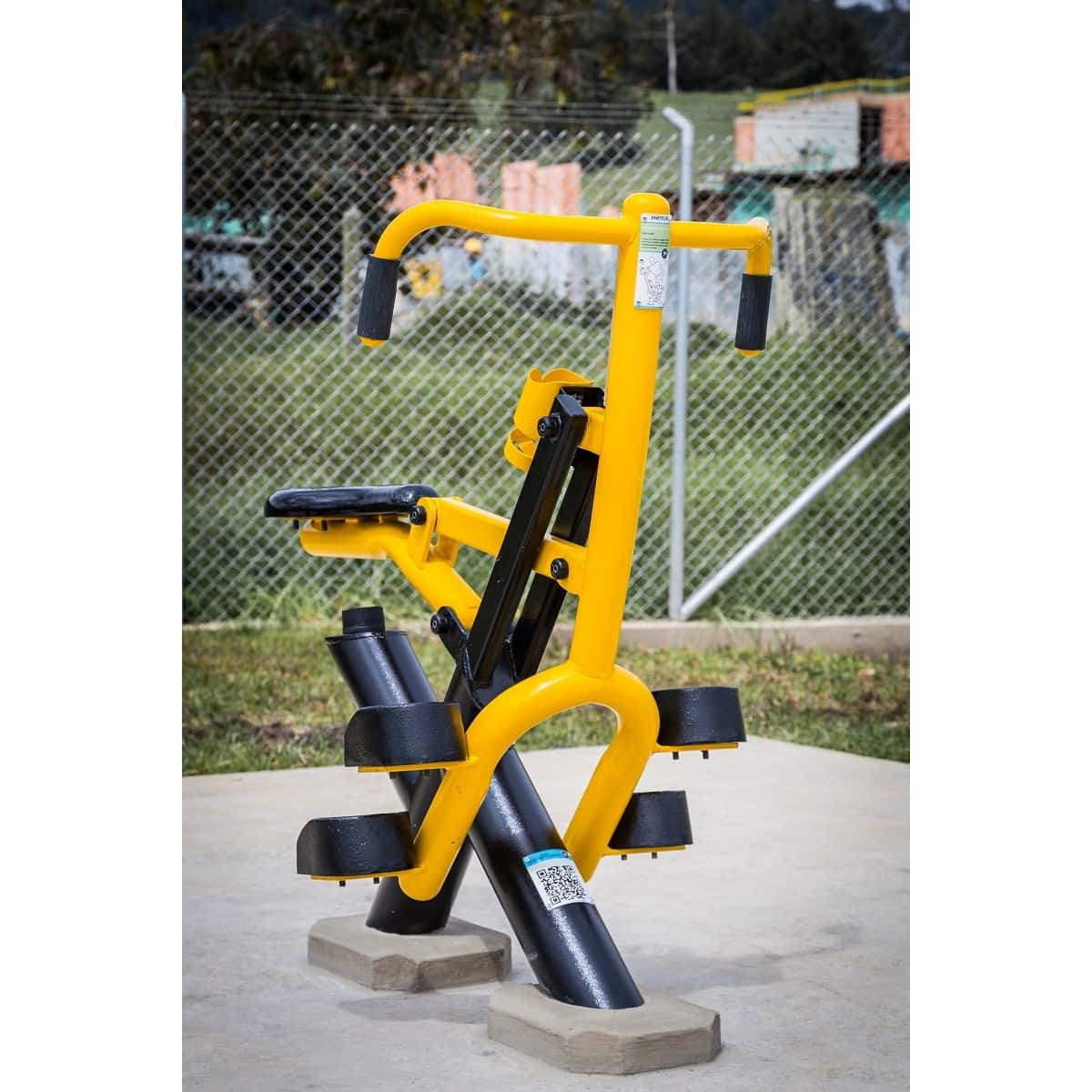 Jinete de TMGYM, equipo de gimnasio al aire libre amarillo y negro sobre piso de concreto en un parque