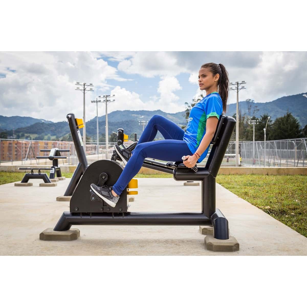 Mujer pedaleando en la bicicleta recumbent de TMGYM con montañas al fondo