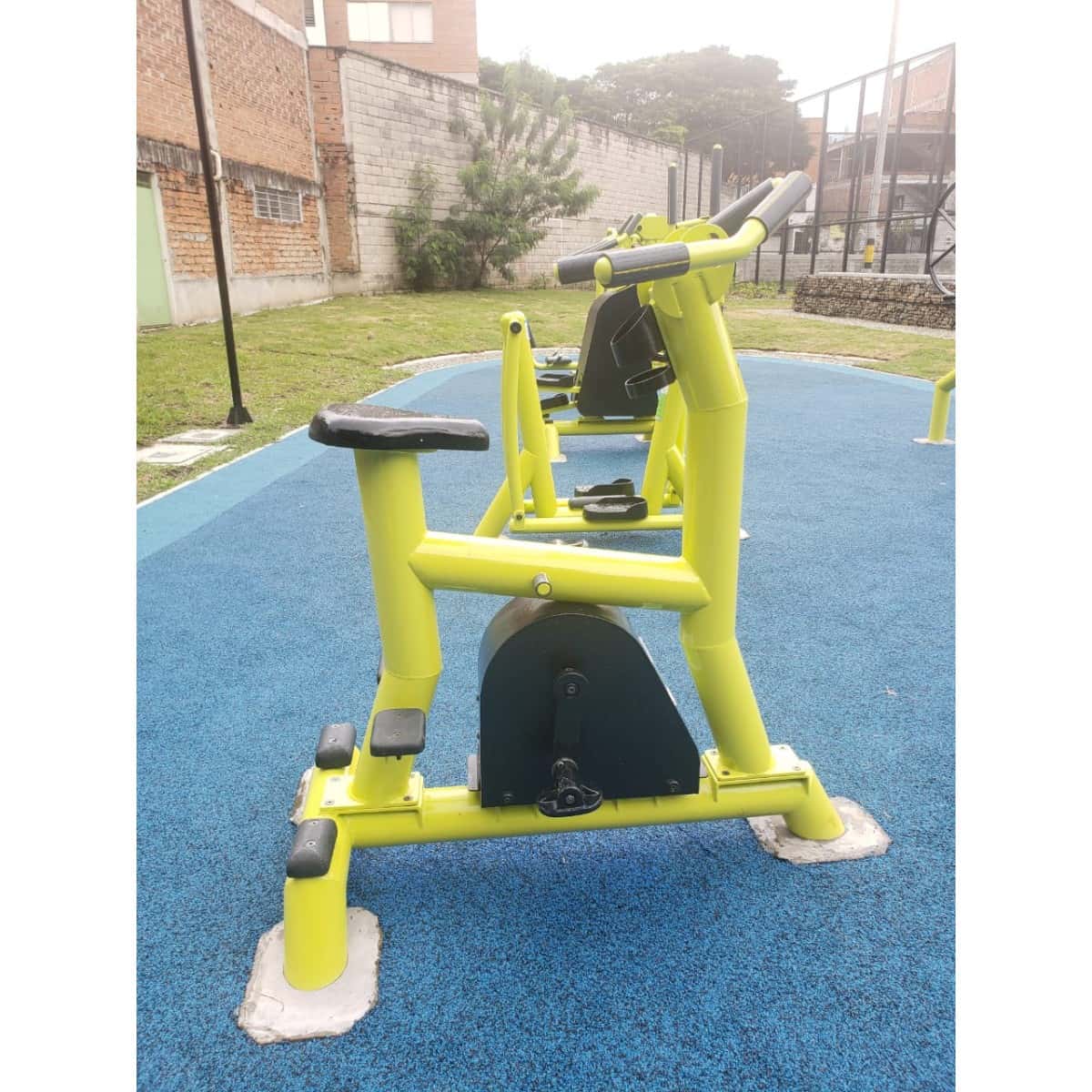 Bicicleta estática amarilla de TMGYM sobre piso azul, vista lateral