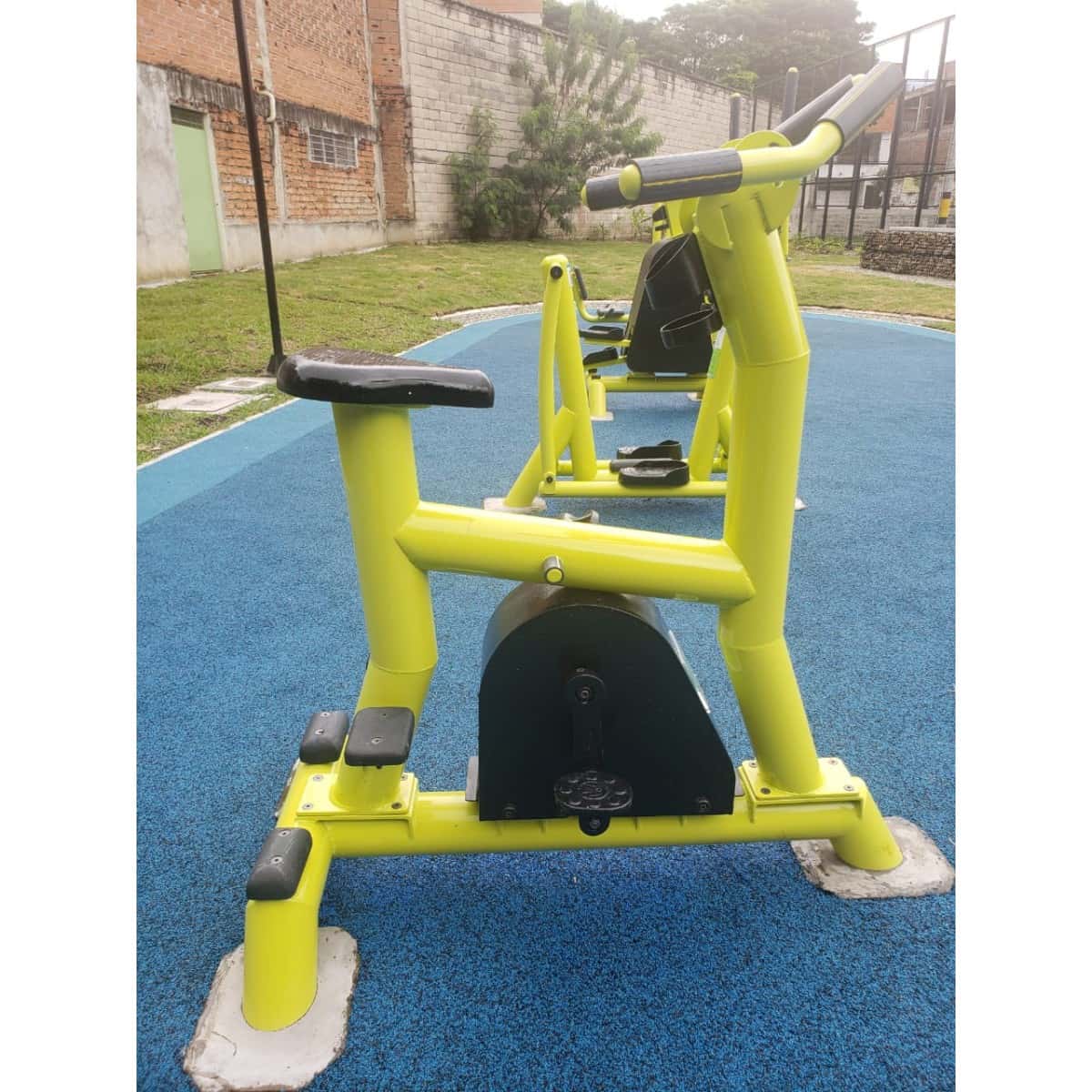 Bicicleta estática amarilla de TMGYM con árboles al fondo