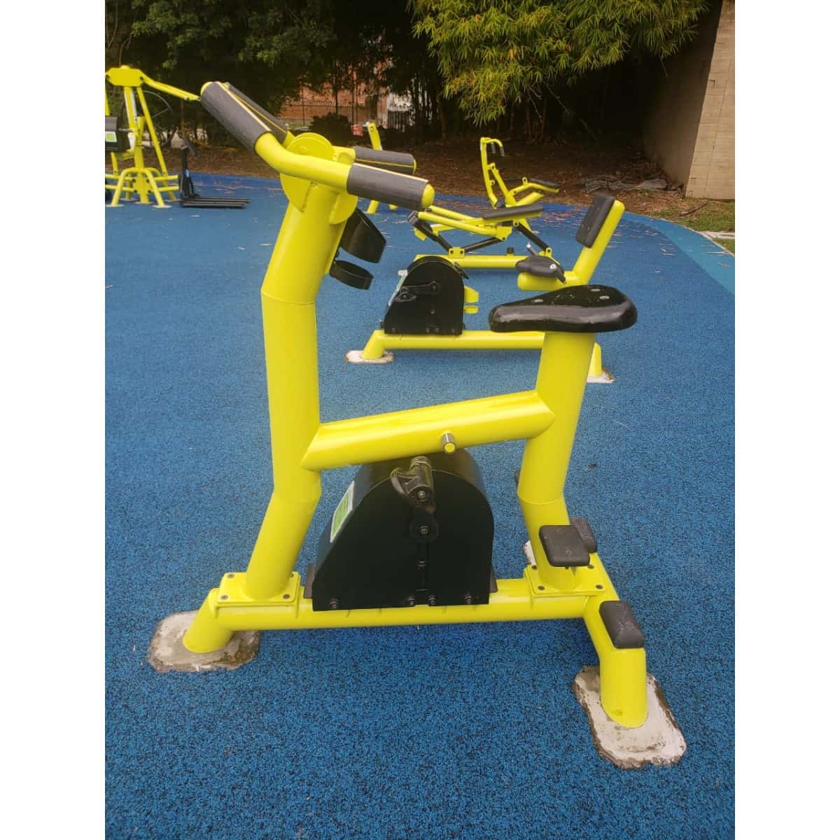 Bicicleta estática de TMGYM, equipo amarillo para parque sobre piso azul