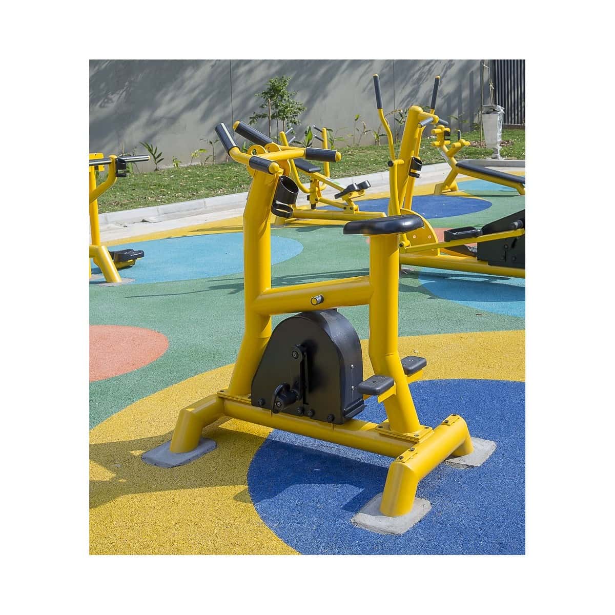 Bicicleta estática de TMGYM sobre piso de colores en una zona de juegos
