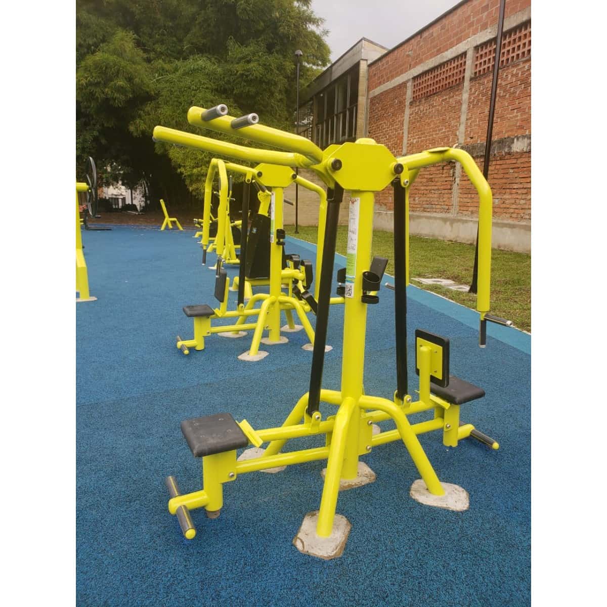 Jalón de espalda doble amarillo de TMGYM sobre piso azul junto a otros equipos
