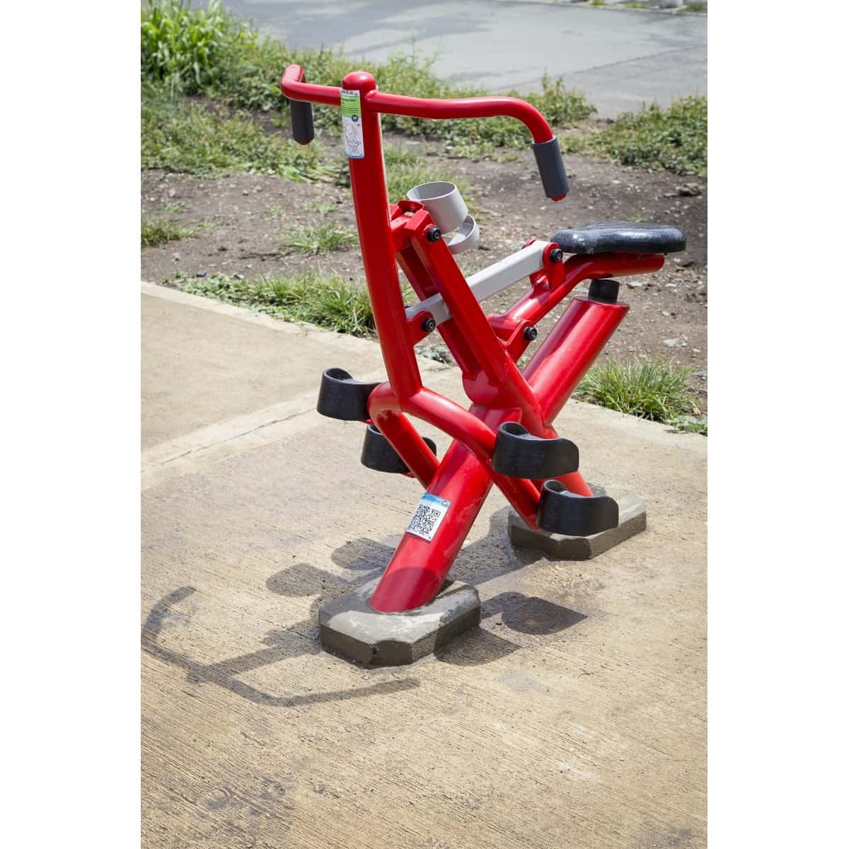 Jinete rojo de TMGYM sobre piso de concreto con pasto al fondo