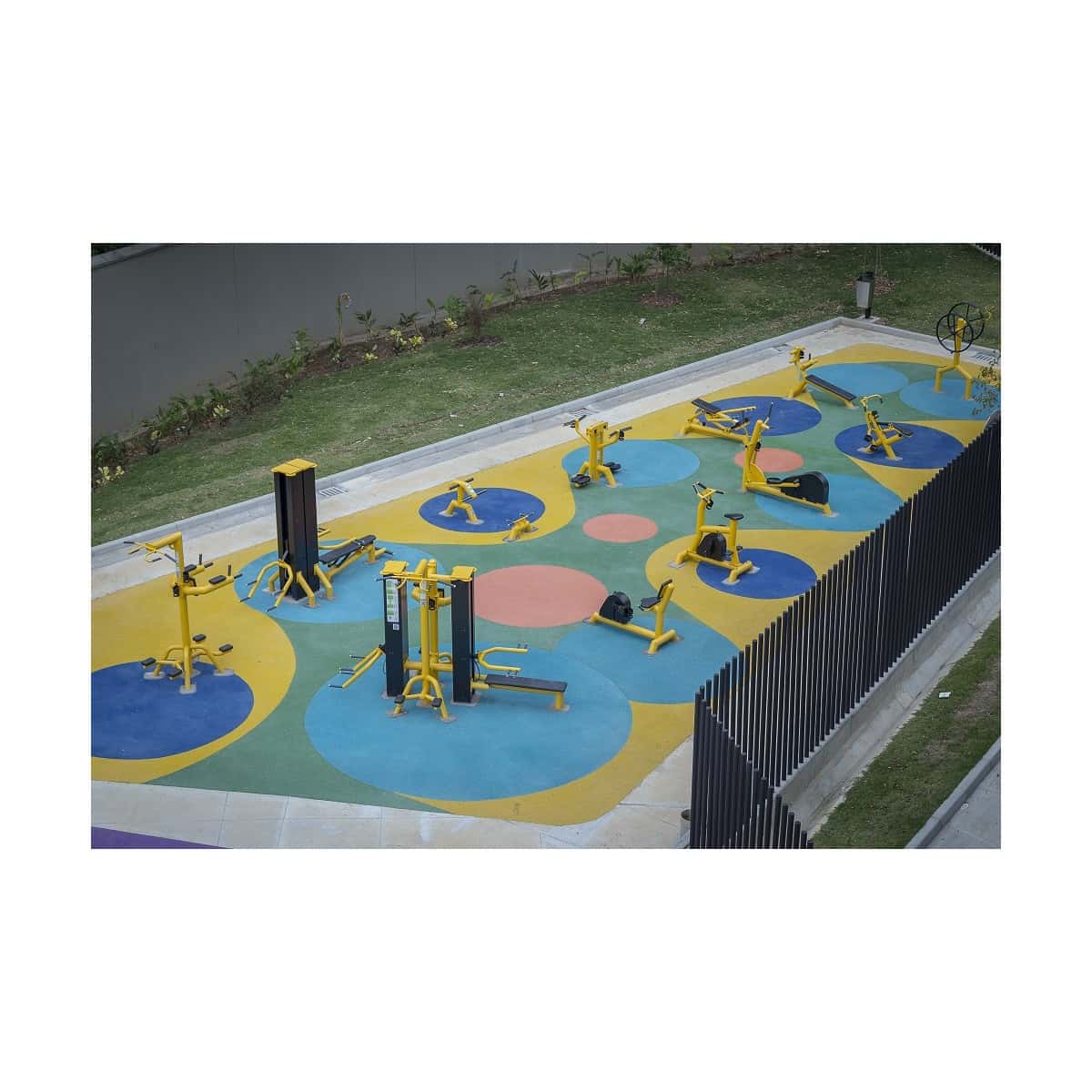 Zona de equipos de gimnasio al aire libre de TMGYM sobre piso de colores