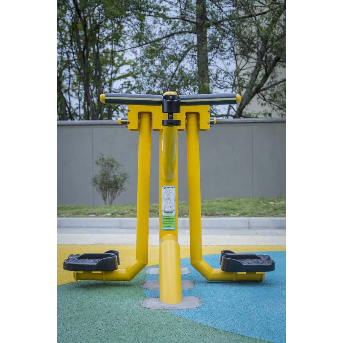 Péndulo de TMGYM amarillo junto a un muro en un parque, vista frontal