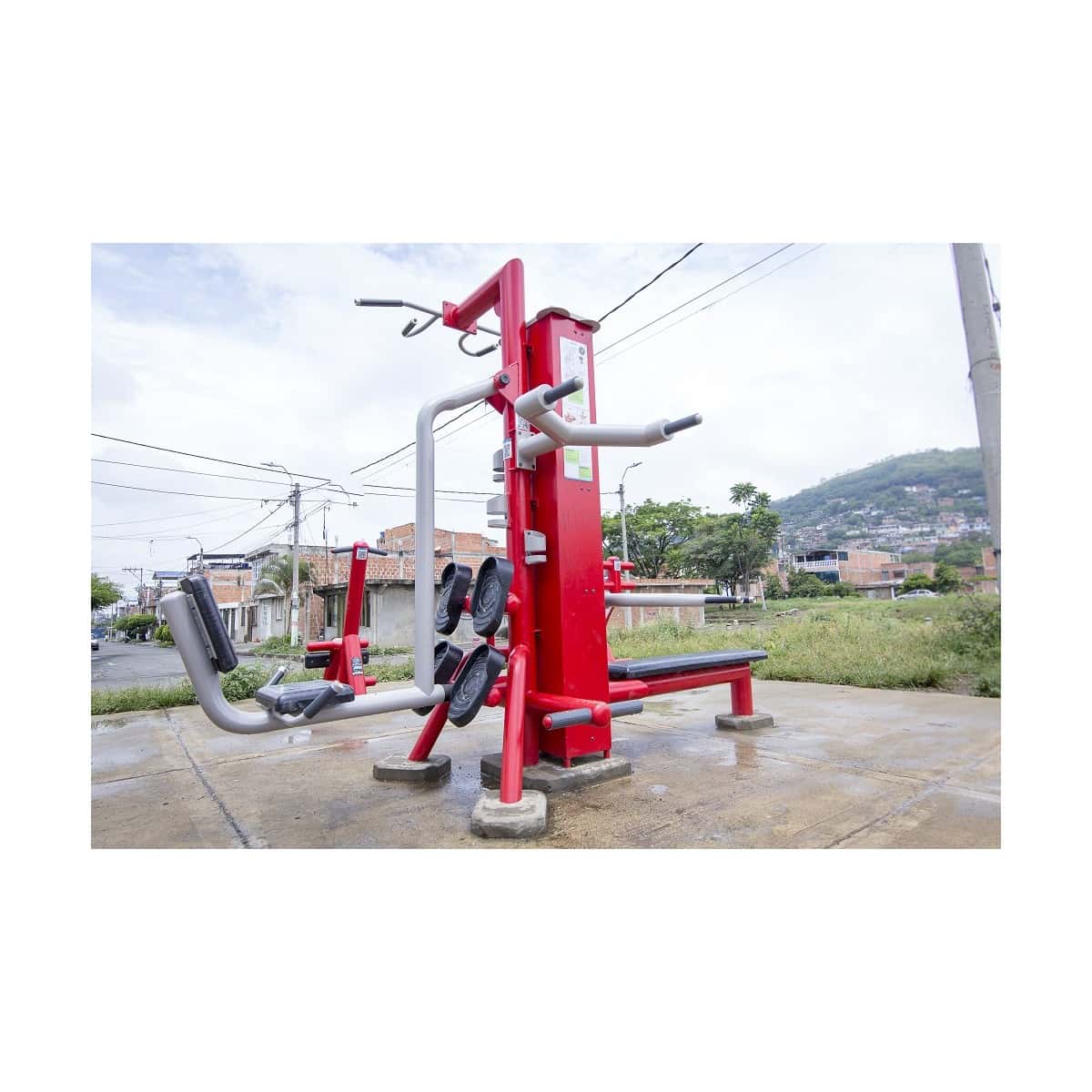 Prensa de piernas doble de TMGYM, equipos rojos y grises en un parque