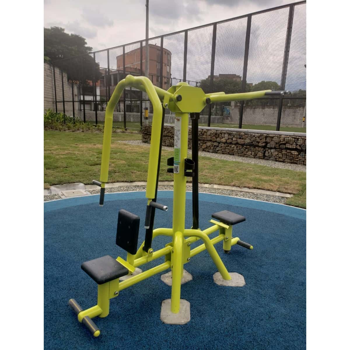 Prensa de pecho doble amarilla de TMGYM con una malla al fondo