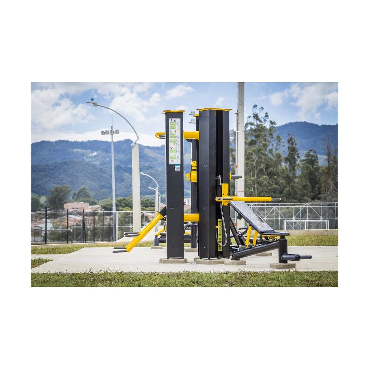 Torre de sentadillas de 150 libras de TMGYM, torre negra con agarres amarillos en un parque con montañas al fondo