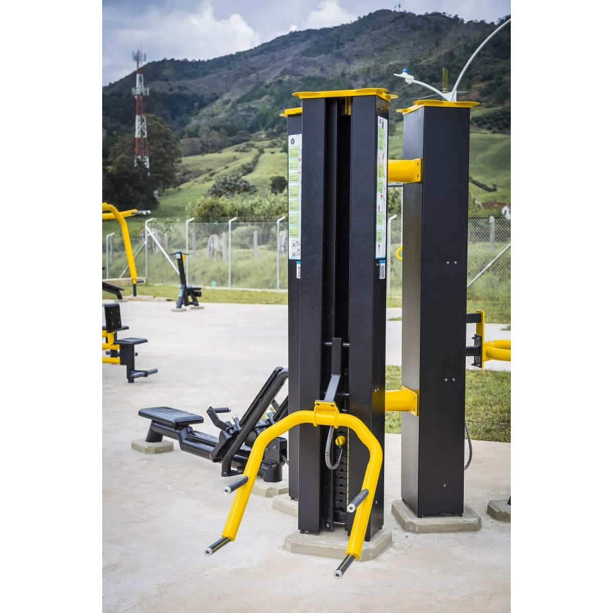 Torre de sentadillas de TMGYM negra y amarilla sobre concreto con montañas al fondo