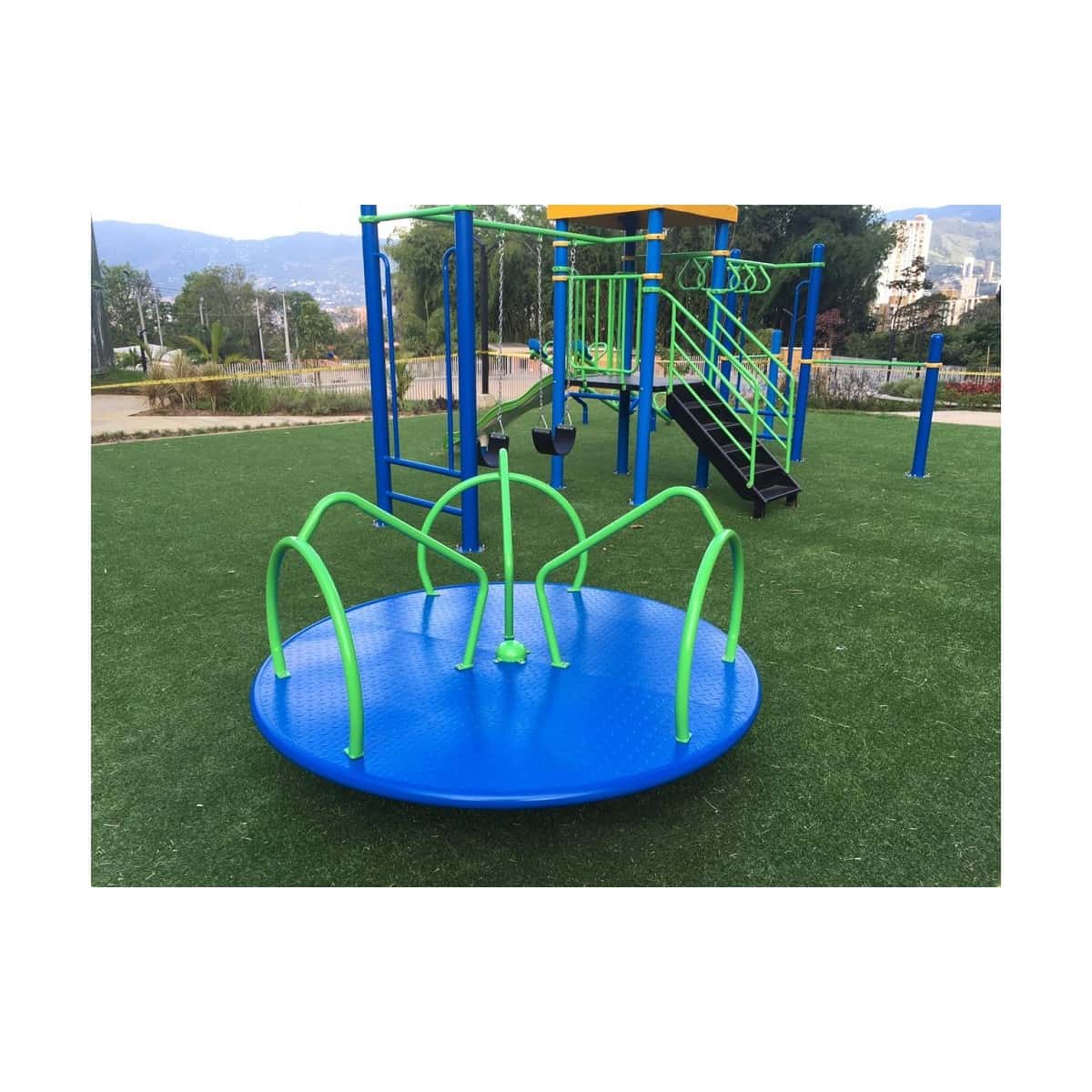 Carrusel azul con arcos verdes sobre grama sintética en un parque infantil recreativo