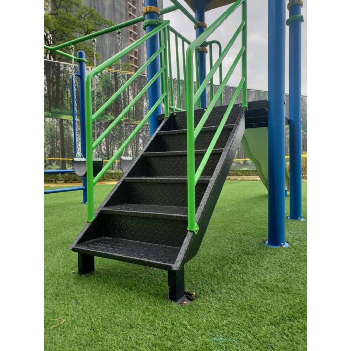 Escalera de peldaños negros y barandas verdes de un parque infantil recreativo