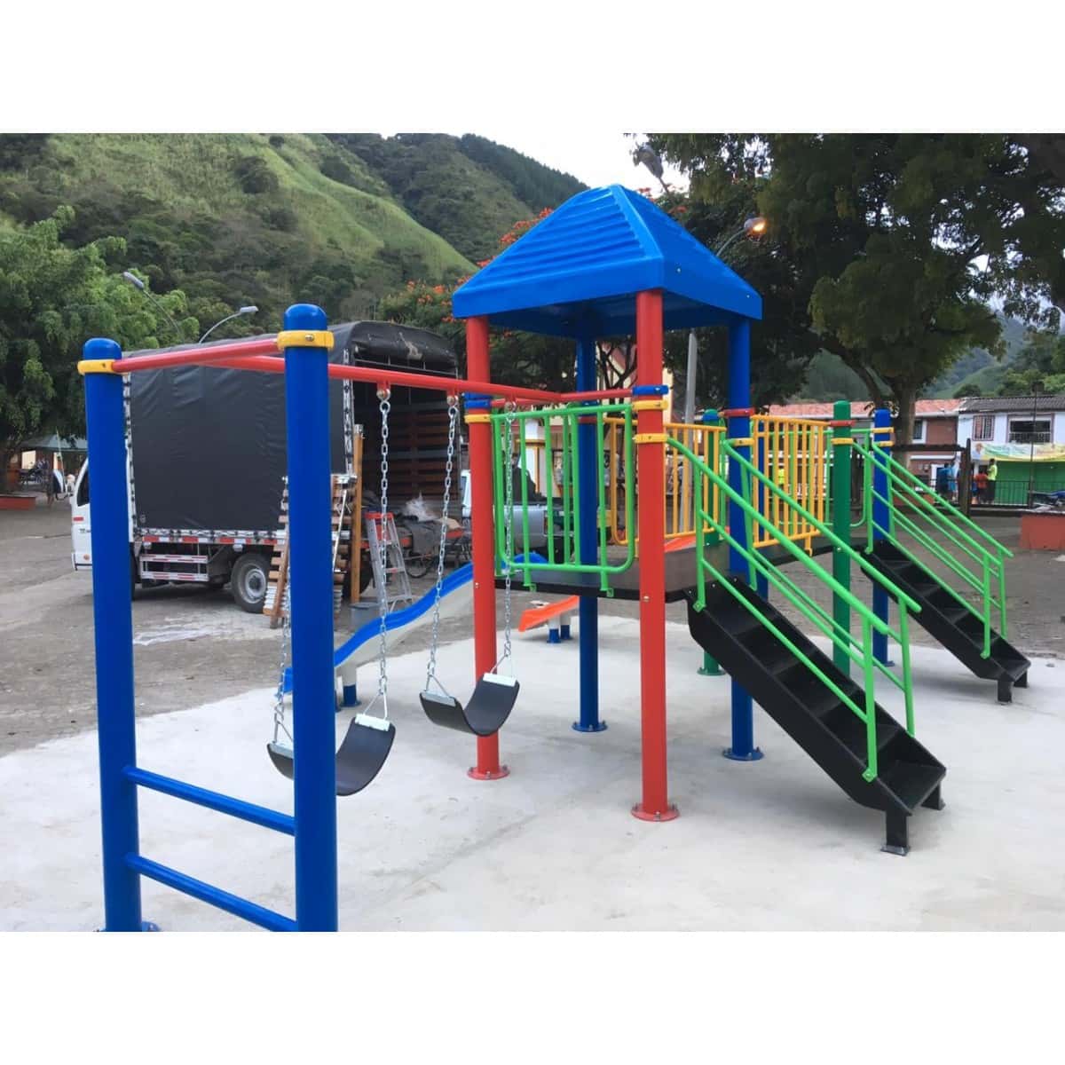 Parque infantil con techo azul, deslizaderos naranja y azul y escalera de barras sobre piso de concreto