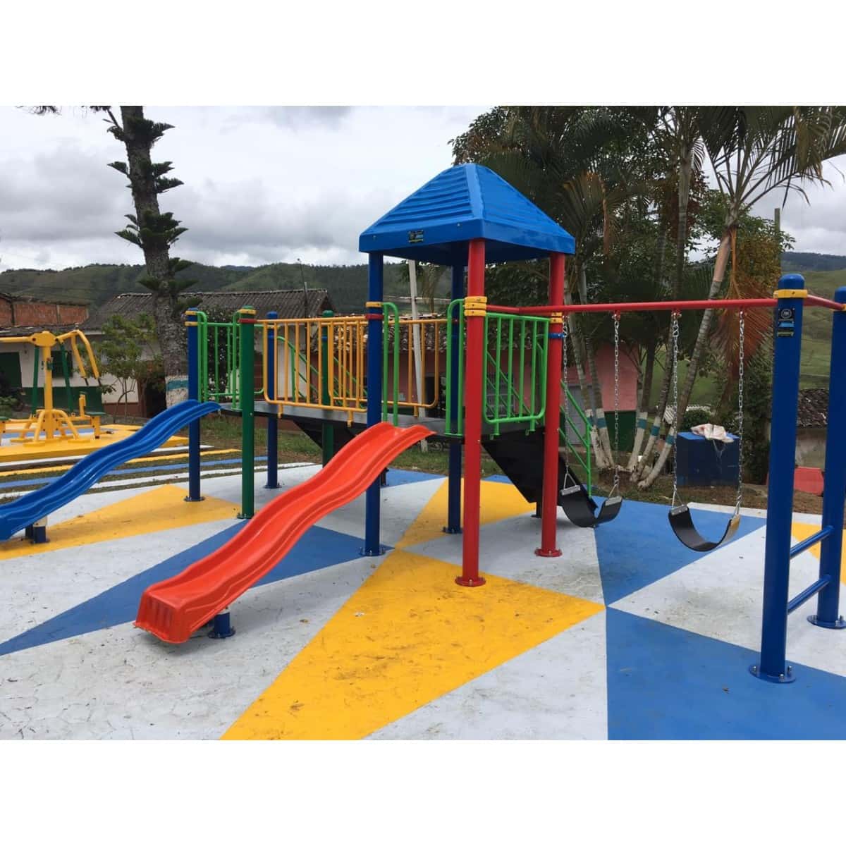 Parque infantil con deslizaderos rojo y azul sobre piso pintado de colores