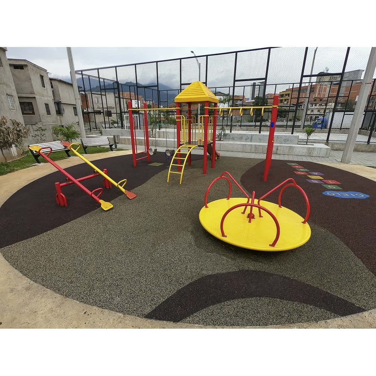 Parque infantil recreativo metálico con carrusel, balancines y juegos de estructura roja sobre piso oscuro