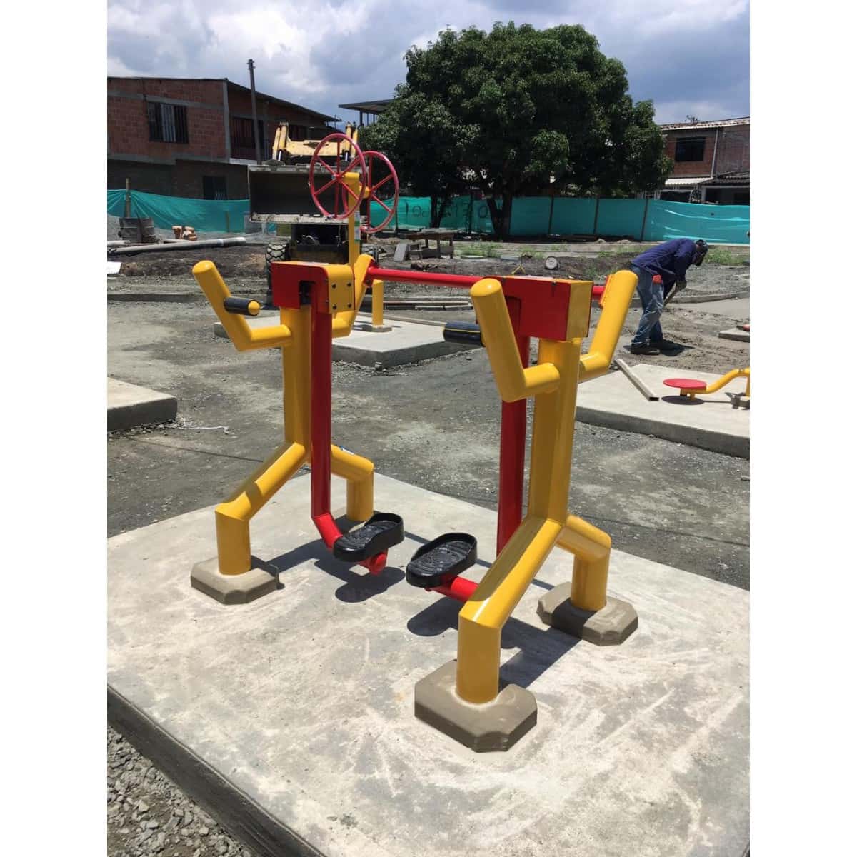 Aero Sky sencillo de TMGYM, equipo de cardio rojo y amarillo sobre una plataforma de concreto en un parque