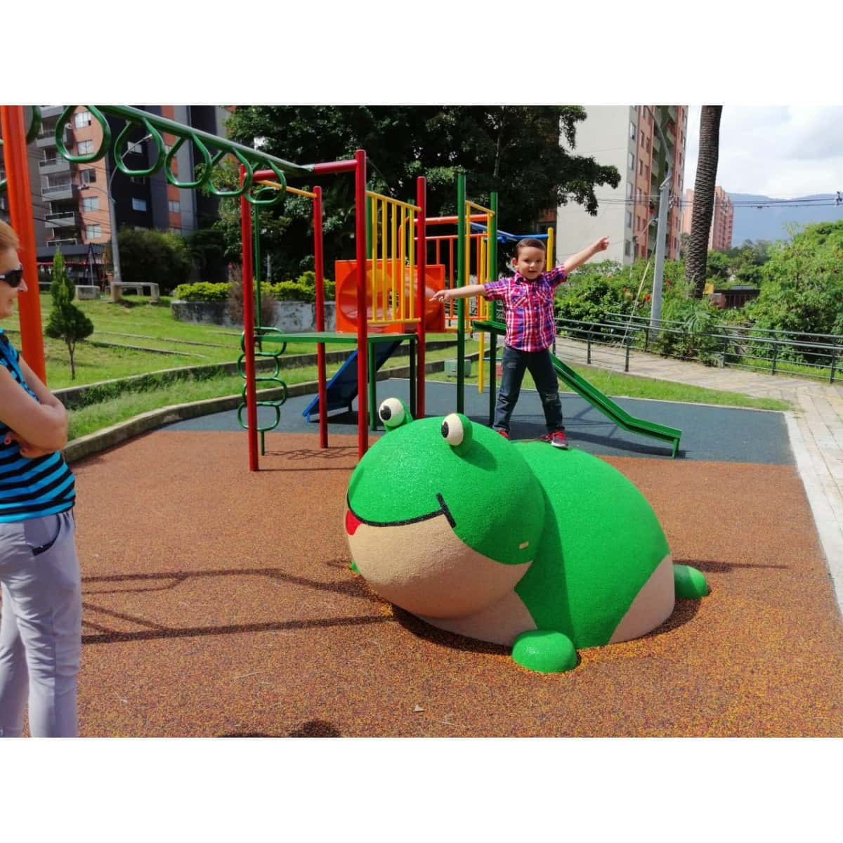 Niños junto a una figura 3D de rana en un parque infantil