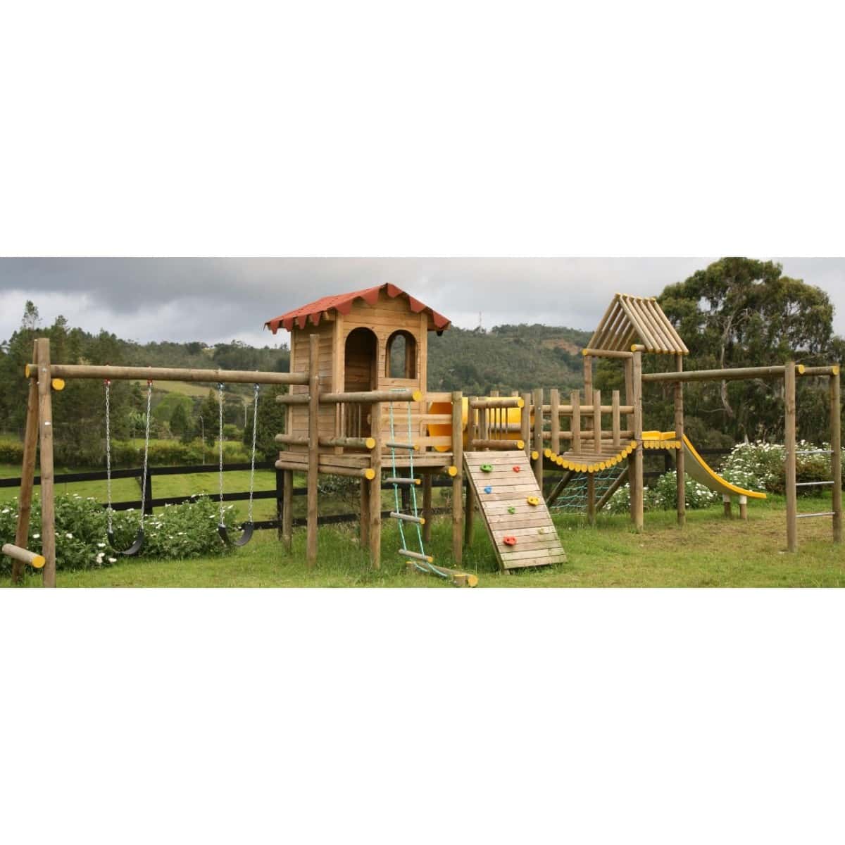 Parque Casa de los sueños instalado en un campo: casa de madera con puente y pared de escalada