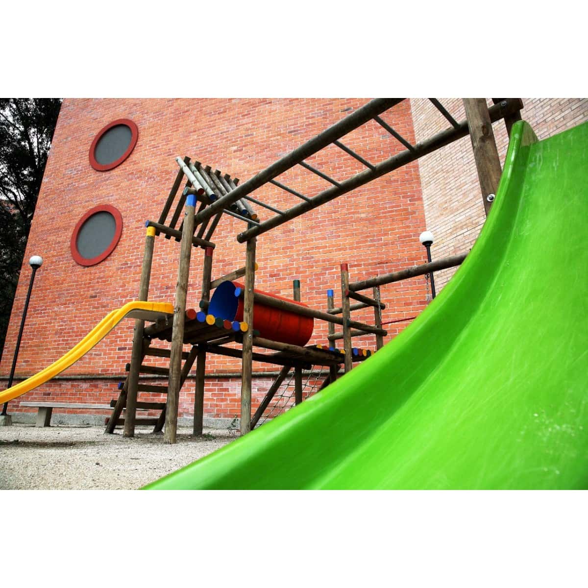 Deslizaderos verde y amarillo del Parque Doble Diversión instalado junto a un edificio de ladrillo