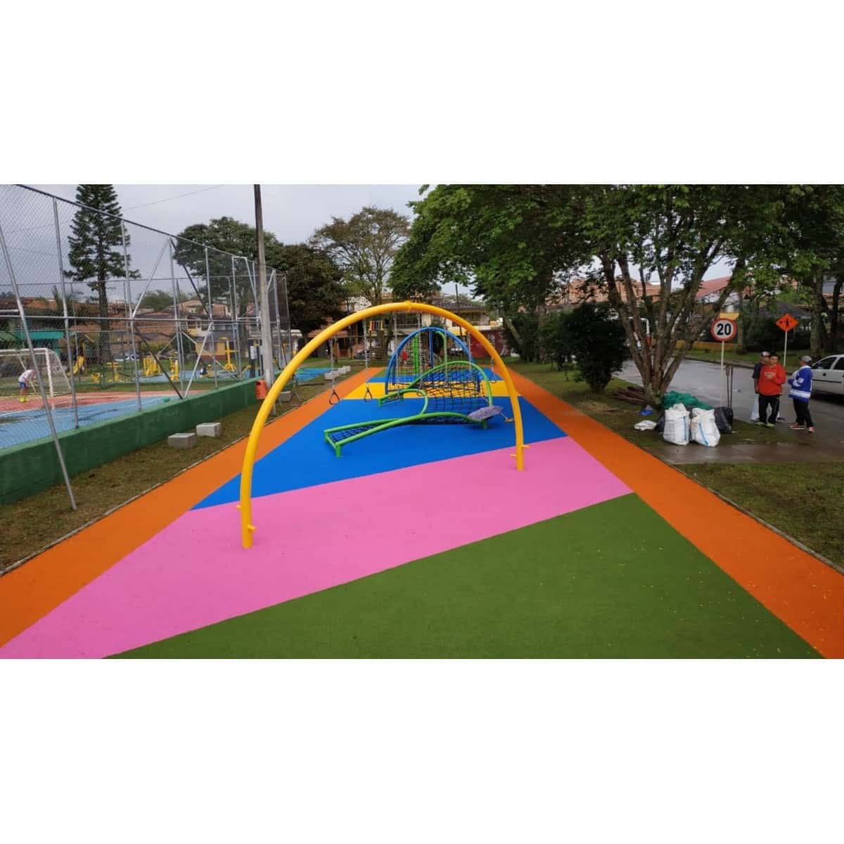 Zona de juegos infantiles con piso sintético de colores y una estructura de juego curva al fondo