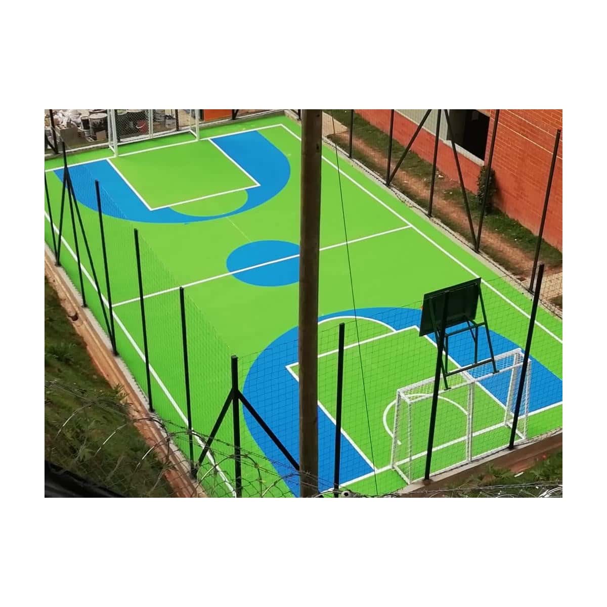 Cancha de coliseo pintada en azul y verde, con líneas de demarcación y aro de baloncesto