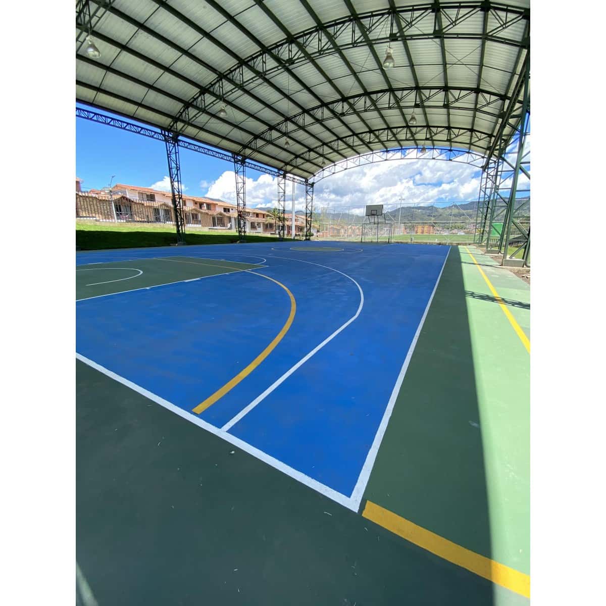 Cancha de coliseo pintada en azul y verde con líneas de demarcación