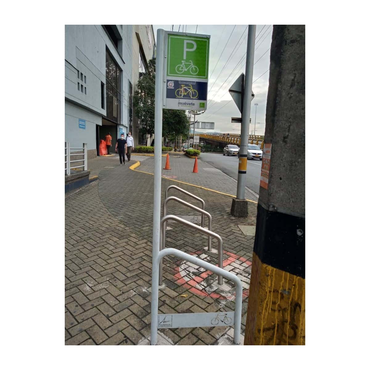 Parquearos para bicicleta en un andén, con la señal de parqueadero