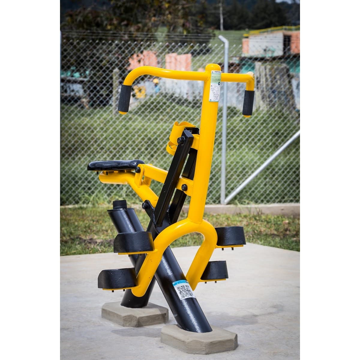 Jinete de TMGYM, equipo de gimnasio al aire libre amarillo y negro sobre piso de concreto en un parque