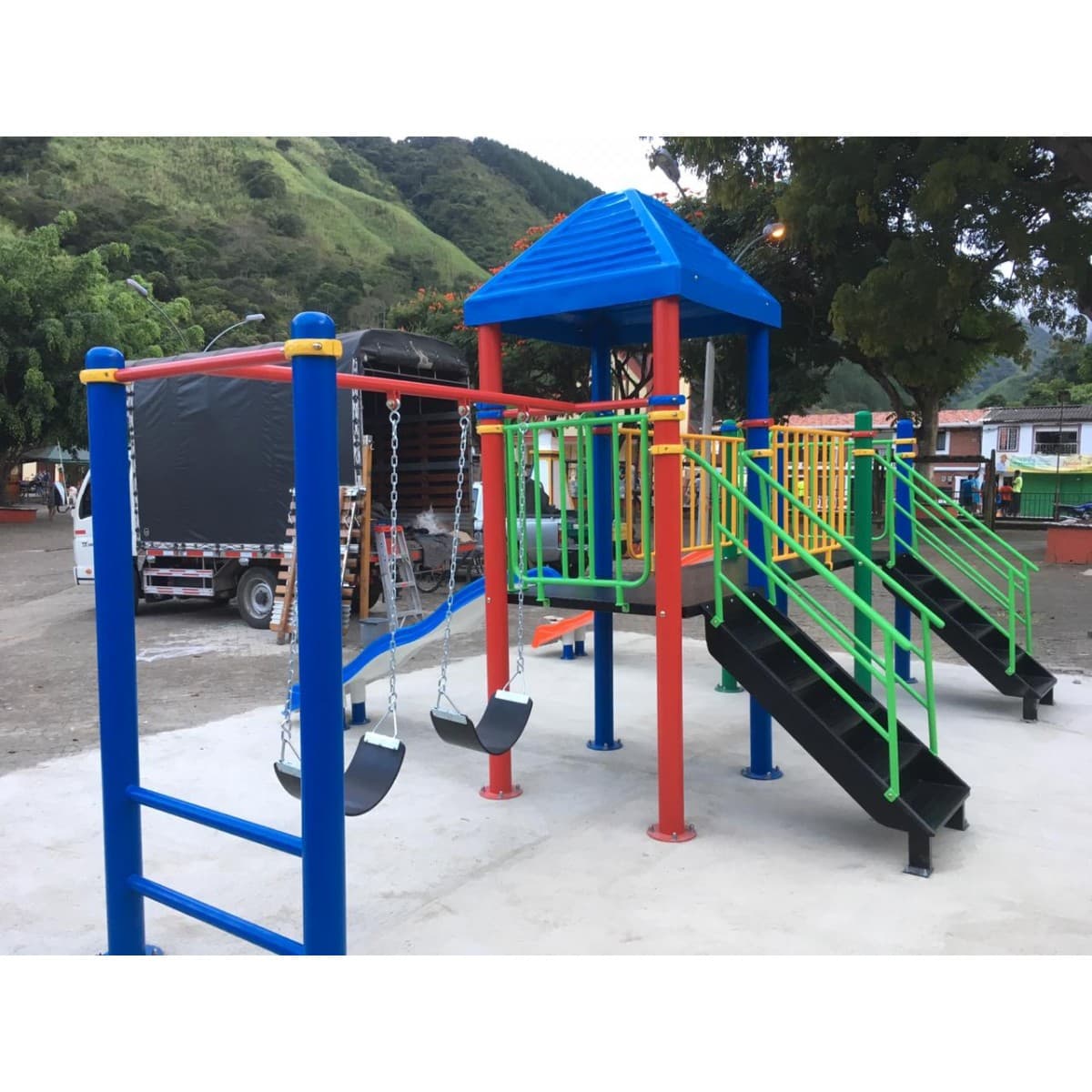 Parque infantil con techo azul, deslizaderos naranja y azul y escalera de barras sobre piso de concreto